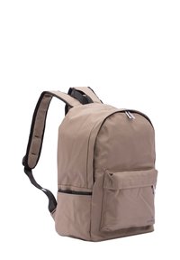 Sac à dos tan en tissu lisse avec des coutures renforcées, des bretelles rembourrées, une poche avant et une fermeture zippée sur le dessus.