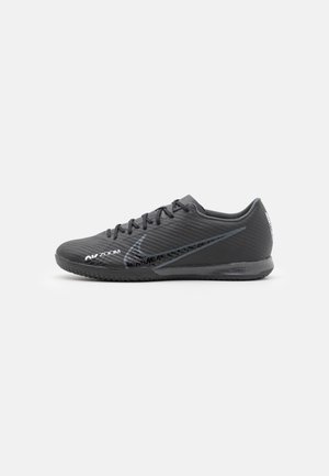 Chaussure de sport Nike noire profil bas avec lacets, surface texturée, et marquage "Air Zoom" visible sur un fond clair uni.