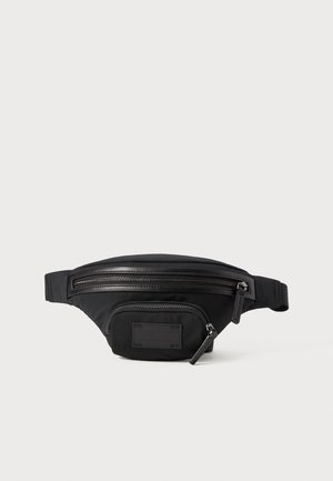 Czarna nerka z nylonu o gładkiej powierzchni, z dwiema zapinanymi na zamek kieszeniami, naszywką z logo oraz regulowanym paskiem.