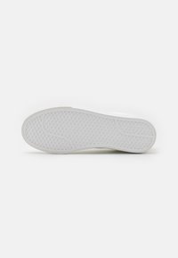 Hvit sneakersåle med et teksturert, bikubemønster. Gummimateriale, rund form med en lett kurve ved tå og hælområdet.