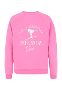 Roze sweatshirts met raglanmouwen. Bevat witte tekst en grafiek: "HET IS EEN LEVENSTIJL SKI & SNOW Club" met een skifiguur. Zachte textuur.