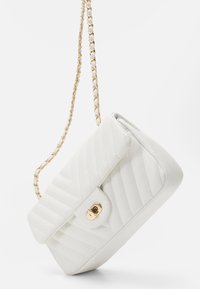 Klejcowa, biała torebka na ramię z pikowanego skóry z złotym łańcuszkiem i złotym zapięciem. Posiada usztywniony kształt i gładką fakturę.