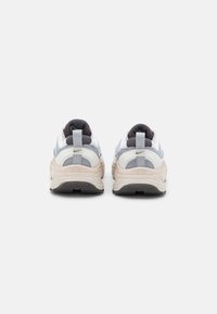 Coppia di sneakers Nike beige e grigie viste da dietro con anelli per il tiraggio e ammortizzazione a vista nella suola.