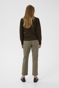 Maglione marrone a maglia con maniche lunghe, abbinato a pantaloni verde oliva e scarpe nere, visto da dietro.