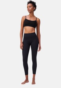 Zwarte sportbeha met dunne bandjes en logo-band; hoge taille zwarte leggings, fitted snit, gladde textuur, enkel-lang.