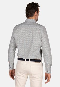 Langermig overhemd met een blauw en wit patroon met rode en groene accenten. Knopf cuffs en een klassieke kraag. Gedwaald met lichte broek.