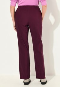 Bordeauxkleurige wijde broek met een elastische tailleband, gemaakt van een gladde stof. Zichtbare naden aan de achterkant en een vlakke voorkant.