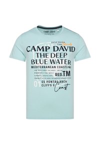 Světle modré tričko s krátkým rukávem, které se vyznačuje výrazným černým a bílým textem, grafickým designem a akcenty v oranžové barvě. Měkký bavlněný materiál.