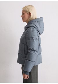 Grau gepolsterte Jacke mit Kapuze, mit gestepptem Design, vorderen Taschen und gerippten Bündchen. Glatte, leicht glänzende Textur.