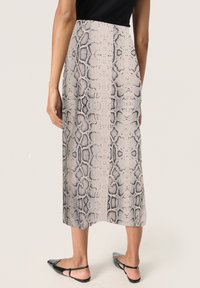 Jupe midi en tissu léger et texturé présentant un motif serpent noir et beige. Coupe lisse et droite avec une taille ajustée.