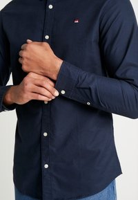 Námořnická košile na knoflíky vyrobená z bavlny s jemnou strukturou, s logem hory na hrudi a knoflíkovými manžetami.