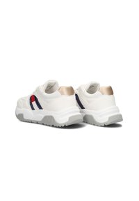 Witte sneakers met een gestructureerde bovenkant, marineblauwe en rode zijaccenten en een gouden hieldetail. Dikke witte zool met een grijs loopvlakpatroon.