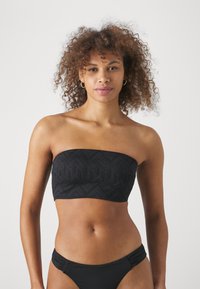 Juodasis bandeau tipo bikini viršus su tekstūruotu geometriniu raštu, lygiais kraštais ir be petnešėlių. Pora su atitinkančiu juodu bikini apatine dalimi.