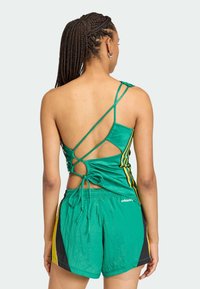 Zelený tielkový top s prekríženým chrbtom, zdobený žltými a čiernymi pruhmi. Kombinovaný so zodpovedajúcimi zelenými šortkami, textúrovaný materiál.