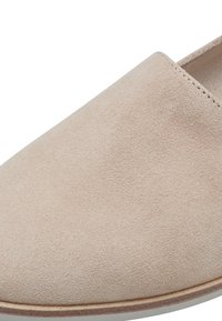 Chaussure slip-on en daim beige avec une texture lisse, un bout arrondi et un design minimaliste. Détails de couture subtils le long du bord.