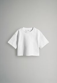 Weißes, cropped T-Shirt aus Baumwolle mit kurzen Ärmeln, runder Halslinie und glatter Textur, vor einem grauen Hintergrund präsentiert.