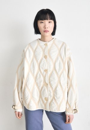 Giacca crema leggermente imbottita con motivo a rombi, caratterizzata da grandi bottoni e una vestibilità rilassata. Accentuata da morbidi dettagli beige.