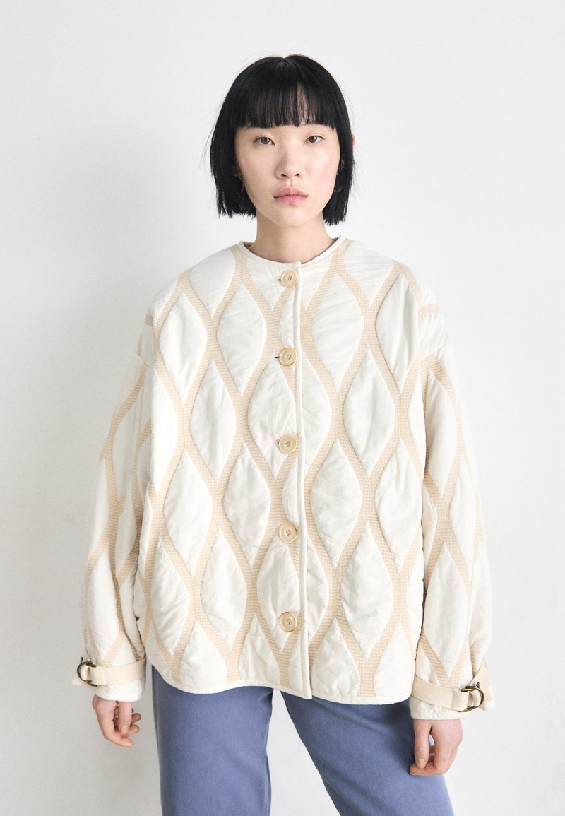 Lightly padded, cream jacket with diamond quilt pattern, featuring large buttons and a relaxed fit. Accented with soft beige details.