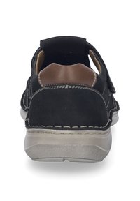 Sorte læder bagside af en sko med brune accenter, der har en Velcro-rem, rund form og struktureret gummisål.