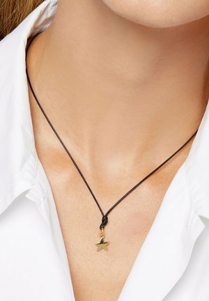 Close-up of a neck with a black cord necklace featuring a small gold star pendant, worn over a white collared shirt.