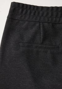 Svarta joggers med en texturerad tyg, elastisk midja och en enda bakficka med en liten klaff. Designen är enkel och funktionell.