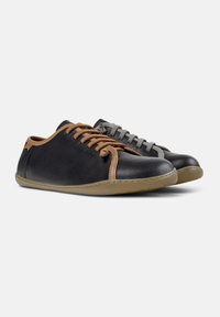 Sneaker nere e grigie con lacci e dettagli marroni, caratterizzate da un design a profilo basso e una suola in gomma flessibile.