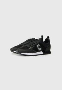 Svarte sneakers med mesh-paneler, gummisåler og hvite detaljer. Har rund tå, snøring og håndtak på hælen.