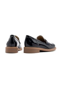 Black patent leather loafers with a smooth finish, featuring a low tan block heel and a rounded toe design. Detailed stitching on the sides.