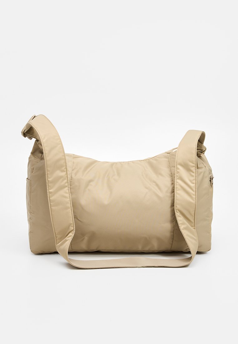 Bolso de hombro acolchado beige con una textura suave y brillante, que cuenta con una correa ajustable y un bolsillo con cremallera en el lateral.