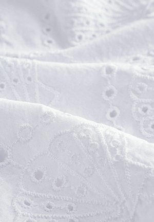 White embroidered fabric with intricate floral patterns and eyelet details. Soft texture with a smooth, lightweight appearance.