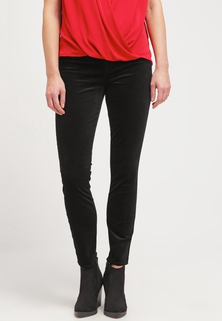 Černé slim-fit kalhoty vyrobené z měkké, strukturované tkaniny. Mají nízký pas a mírně elastický materiál pro pohodlí. V kombinaci s černými kotníkovými botami.