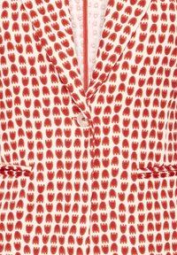 Veste blanche avec motif abstrait de tulipes rouges, fermeture à un bouton, revers crantés et deux poches avant.