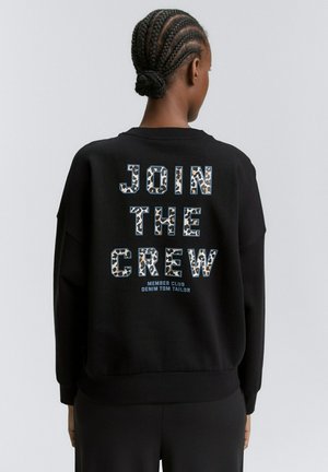 Felpa nera con la scritta "JOIN THE CREW" in lettere a stampa leopardata, con "MEMBER CLUB" e "DENIM TOM TAILOR" stampati sotto. Texture morbida, vestibilità rilassata.