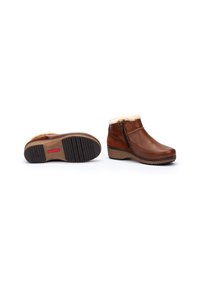 Botas de tobillo de cuero marrón con forro de piel sintética, cremallera lateral, suela marrón texturizada y tacón bajo en cuña. Acabado suave con detalles cosidos.