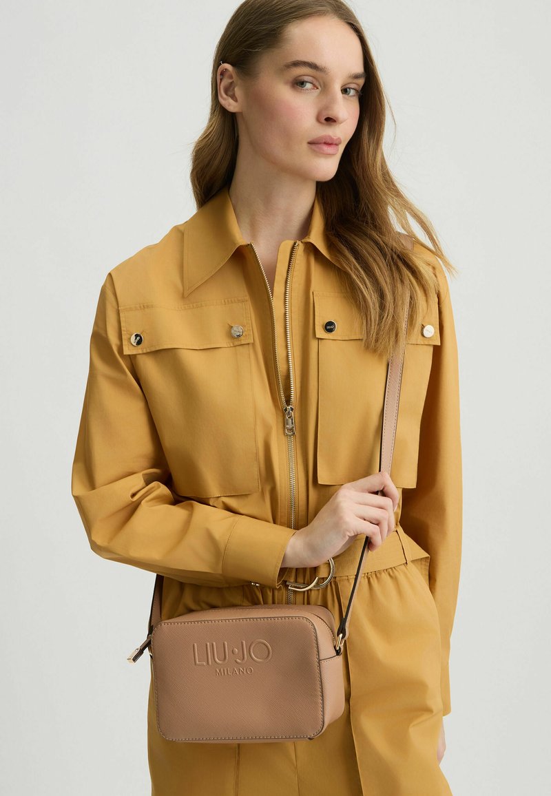 Sac à épaule LIU JO Milano rose clair avec une forme rectangulaire, logo en relief et une bandoulière amovible, présenté sur un fond uni.