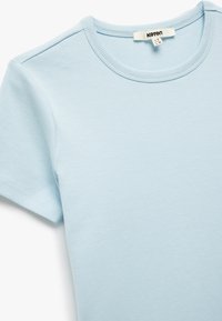 T-shirt in cotone blu chiaro con maniche corte e scollatura rotonda. Presenta una texture morbida e un'etichetta con la scritta "Koton" all'interno.