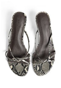 Čierne a krémové sandále so vzorom hada, s tenkými krížovými popruhmi a plochou, hladkou podrážkou, s kontúrovanou stielkou.