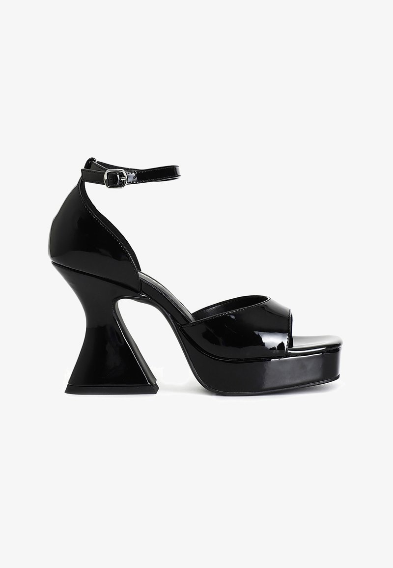 Sort laklæder plateau sandal med buet blokhæl og ankelrem med spænde, vist i sideprofil på hvid baggrund.