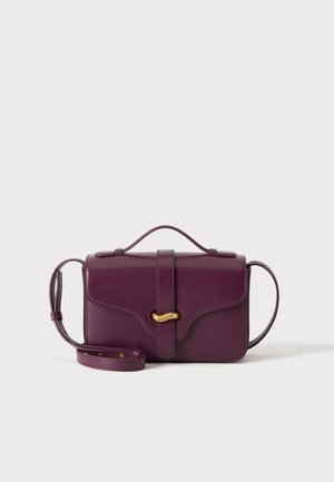 Lilla læder crossbody taske med tophåndtag, frontstroplukning og dekorativ spænde i guldfarve på ensfarvet baggrund.