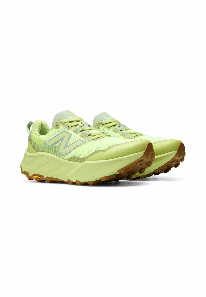 Par de zapatillas de trail running New Balance de color verde claro con suelas gruesas y dibujo de goma marrón, inclinadas para mostrar los lados exteriores y el frente.