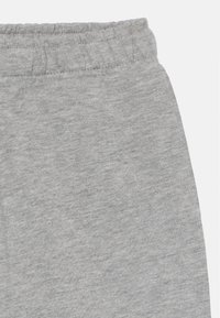 Pantalon de survêtement gris en coton doux avec une taille élastique, présentant une texture lisse et un design à coupe décontractée.