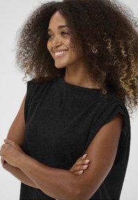 Must mustriga mustriga lühikeste varrukatega top, millel on tagasihoidlik lainemuster. Kangas omab kerget sära ning vaba lõikega siluetti.