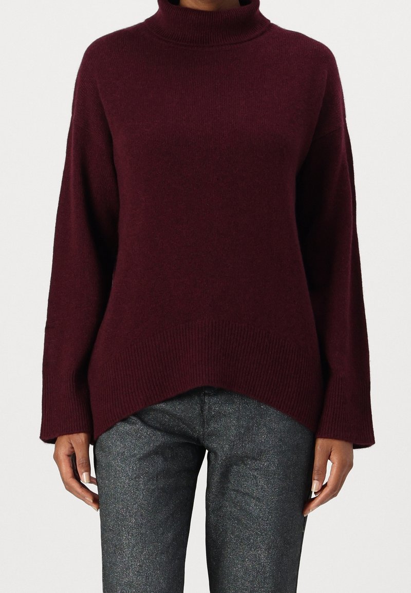 Burgunderfärgad polo-tröja med långa ärmar, ribbad mudd och hög-låg fåll, tillverkad av mjukt stickat tyg med en strukturerad yta.