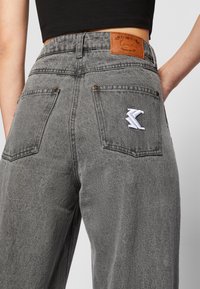 Grå høyt liv denim jeans med en teksturert finish, med et lærpatch og en brodert logo på baklommen.