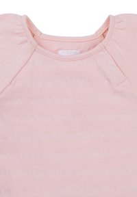 Jasnoróżowy bawełniany top z okrągłym dekoltem, delikatnymi falbanami na ramionach oraz zapięciem na napy z boku.