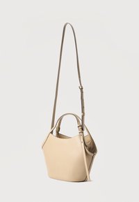 Μπεζ δερμάτινη τσάντα χειρός με κυρτή κορυφή, κοντές λαβές και ρυθμιζόμενο μακρύ ιμάντα ώμου σε απλό φόντο.