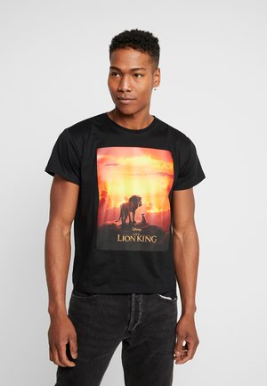 T-shirt en coton noir avec un graphique coloré "Le Roi Lion" représentant un lion et son petit sur fond de coucher de soleil. Manches courtes et col rond.