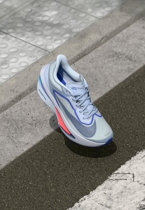 Baskets Nike Zoom Fly 06 en bleu clair avec tige en maille, accents violets et détails rouges sur la semelle. Bout arrondi et système de laçage.