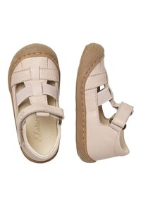 Zapatos infantiles de cuero rosa con punta redondeada, correas elásticas cruzadas y suela de goma color marrón, con pequeños cortes para mejorar la transpirabilidad.