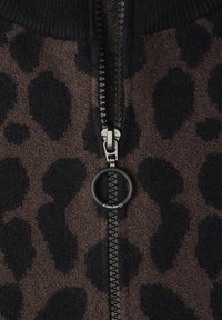 Hnědý pletený svetr na zip s černými leopardími skvrnami, s kovovým zipem s kulatým tahákem. Texturovaná látka a žebrované detaily na límci.